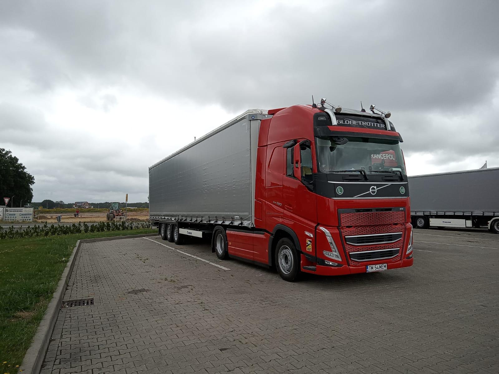 Camion Volvo roșu cu semiremorcă prelată Transmen